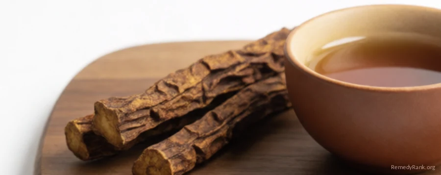 Dried brown licorice root sticks beside a small cup of amber tea.