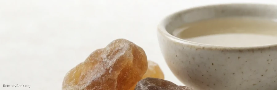 Amber-brown myrrh resin tears beside a small bowl of pale liquid.