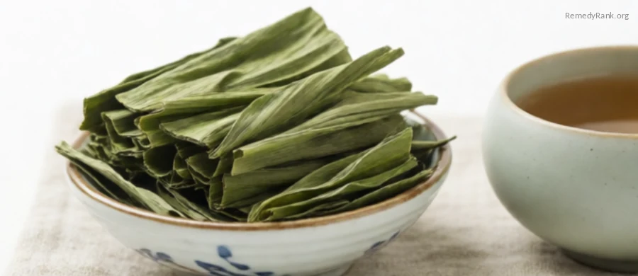A bowl of dried ribbed green plantain leaves beside a ceramic teacup.