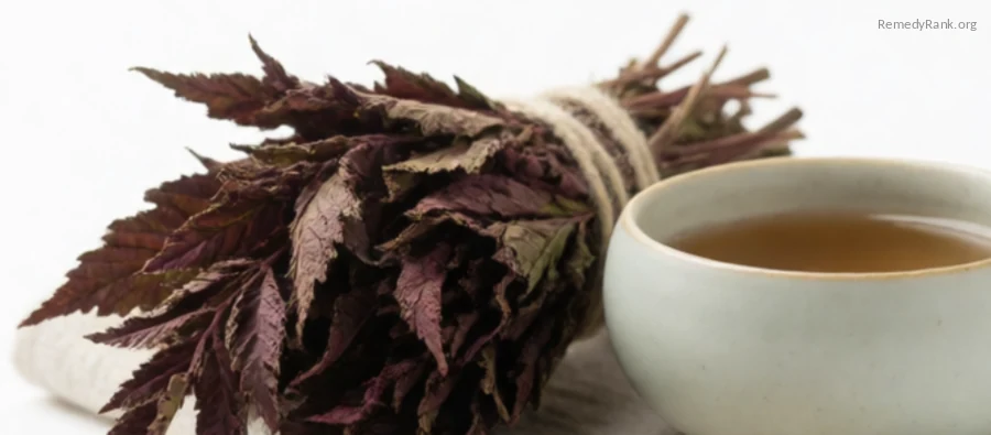 A bundle of dried red raspberry leaves beside a ceramic teacup.